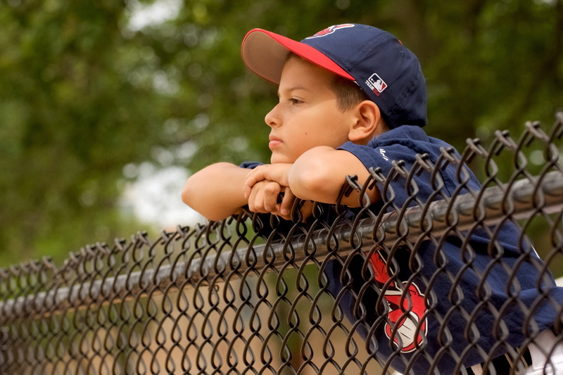 fence, one boy only, children only, dreaming, game, baseball, sport, fan, leaning, day, outdoors, watching, boundary, one person, contemplation, hat, childhood