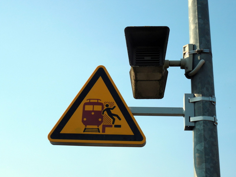 railway station, camera - photographic equipment, road, guidance, light, communication, shape, outdoors, low angle view, sign, human representation, pedestrian crossing sign