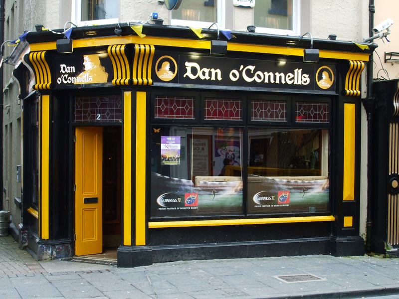 outdoors, day, city, street, ennis pub, 2K, sign, entrance, building exterior, daniel oconnell, mode of transportation, footpath, irish pub, western script