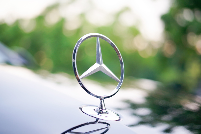 focus on foreground, close-up, eyewear, personal accessory, vehicle logo, outdoors, still life, single object, reflection, jewelry, mercedes benz car logo