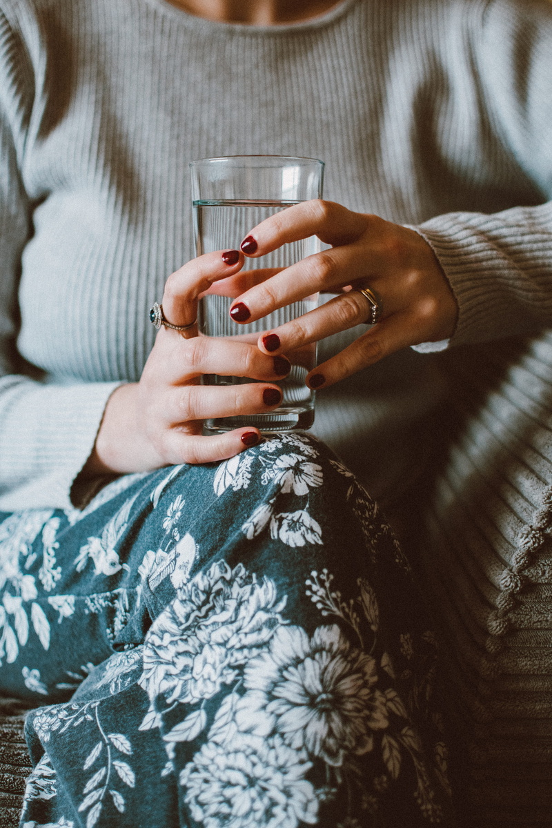 human body part, clear, hand, women, food and drink, wear, skin, grey, glass, young, sofa, hands, sitting, close-up, clothing, glass of water, midsection
