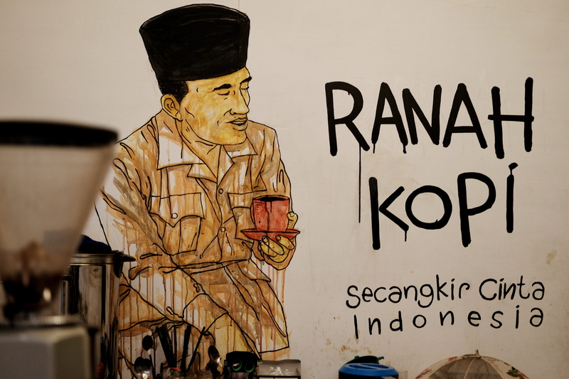 human representation, non-western script, coffee machine, sign, message, creativity, text, mural, government, indoors, male likeness, soekarno, wall - building feature