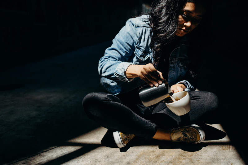 front view, sitting, nose ring, darkness, contemplation, sit, leisure activity, sunlight, denim, young adult, jeans, women, one person, latte, woman, real people
