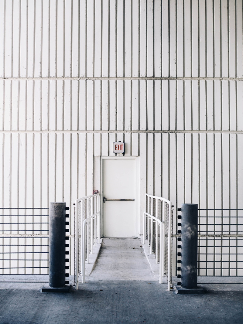 barrier, garbage bin, wall, inside, parking garage, fire escape, exit, location, symmetry, door, architectural, garage, indoors, metal, absence, flooring