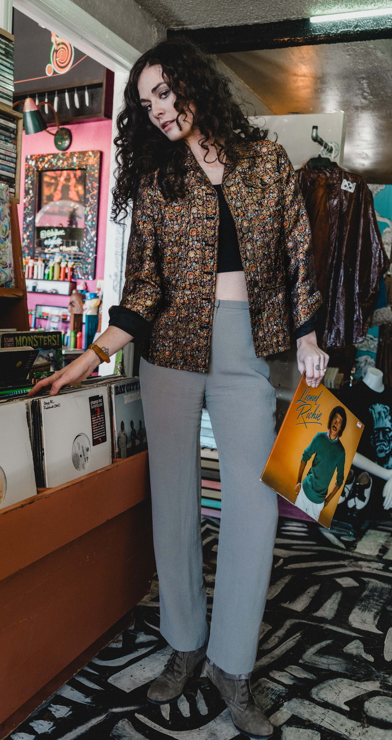 woman, one person, person, pants, record, kiosk, furniture, table, representation, standing, casual clothing, human, indoors, full length, shoe, premiere