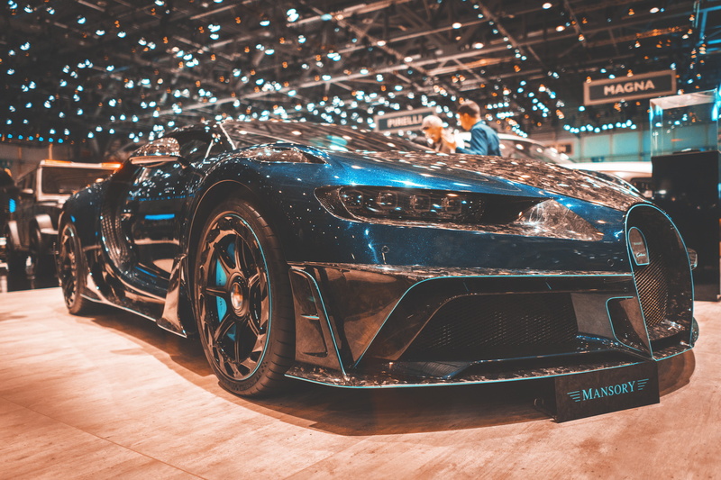 motor vehicle, table, spoke, transportation, wood, machine, building, lit, focus on foreground, auto salon, close-up, sports car, no people, tire, well
