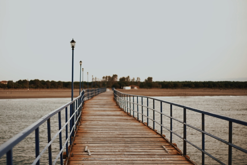 sky, steel, clear sky, pier, seaside, street light, beach, sea, architecture, lighting equipment, water, railings, ocean, built structure, path, jetty