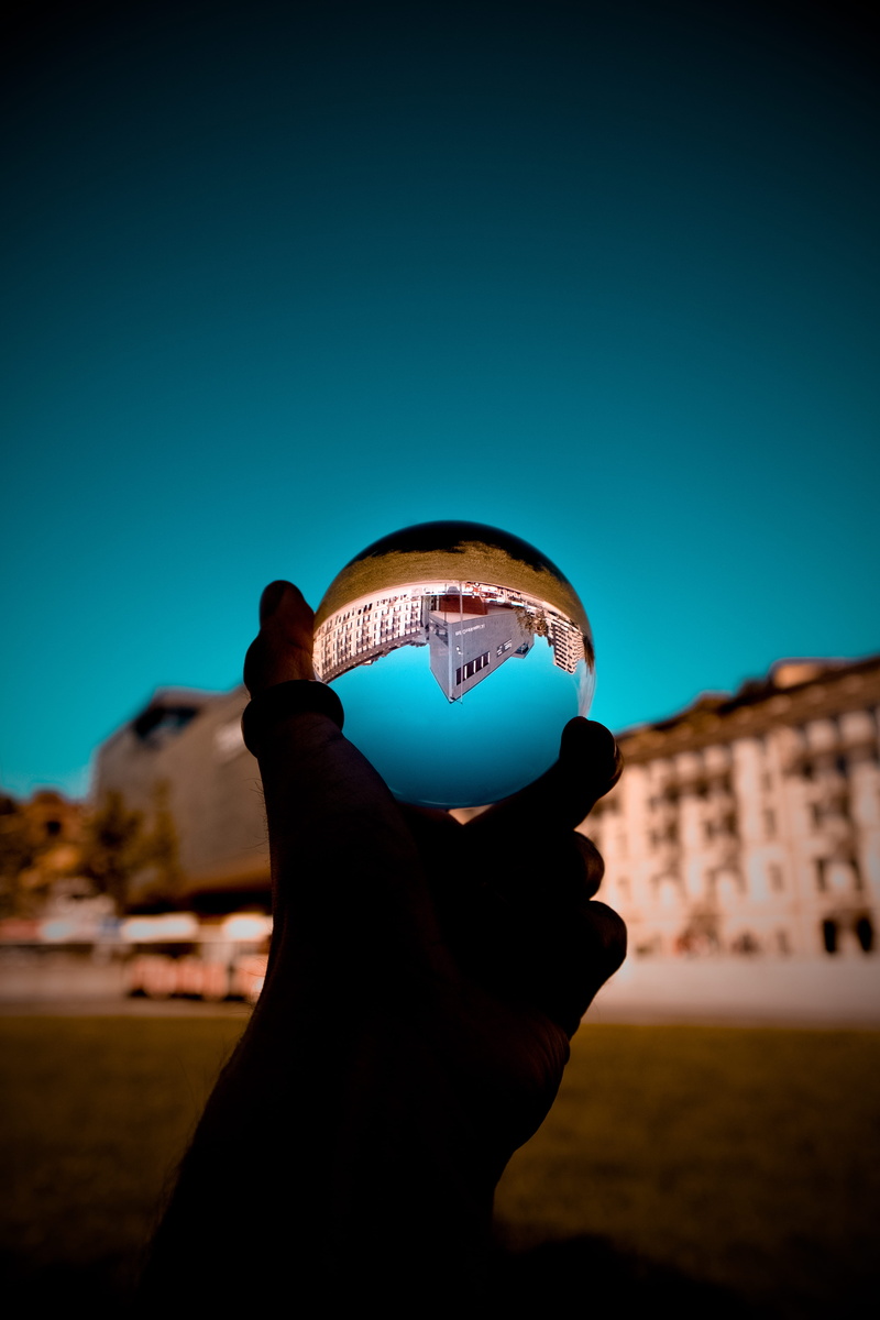 sphere, leisure activity, close-up, built structure, human hand, glass ball, building exterior, 5K, holding, architecture, real people, human body part