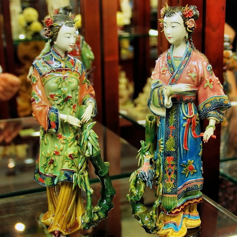 statue, no people, focus on foreground, indoors, ceramic, multi colored, female likeness, market, guangdong, close-up, traditional clothing, day, male likeness