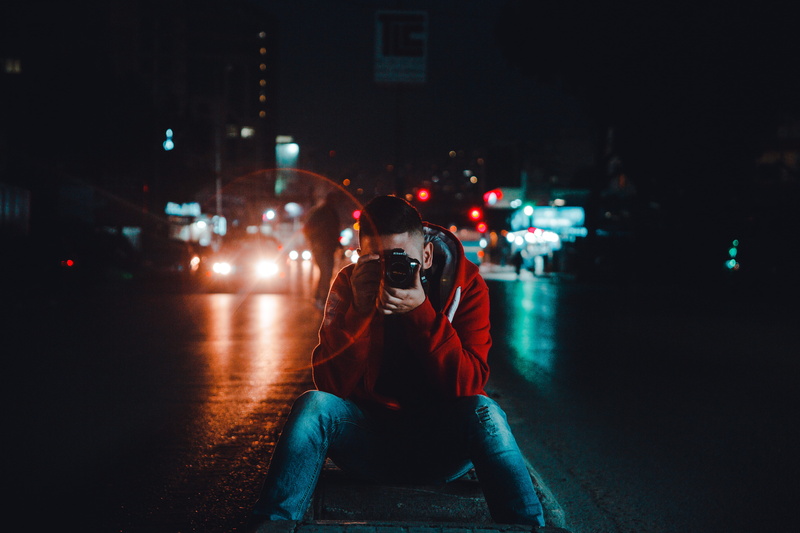 camera - photographic equipment, front view, picture, one person, cars, obscured face, hood - clothing, transportation, car lights, casual clothing, young adult