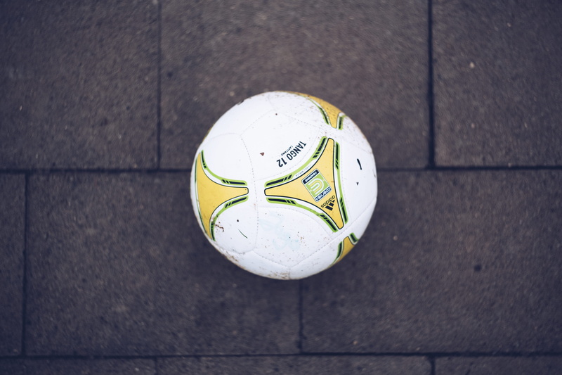 player, tiled floor, day, shape, circle, kid, people, green, soccer, white, geometric shape, person, flooring, design, close-up, pattern, preadolescent