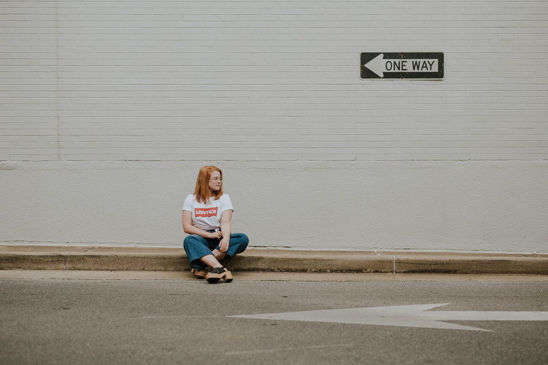 communication, hair, sign, arrow symbol, 5K, city, wall - building feature, road, information, full length, jeans, casual clothing, front view, waiting