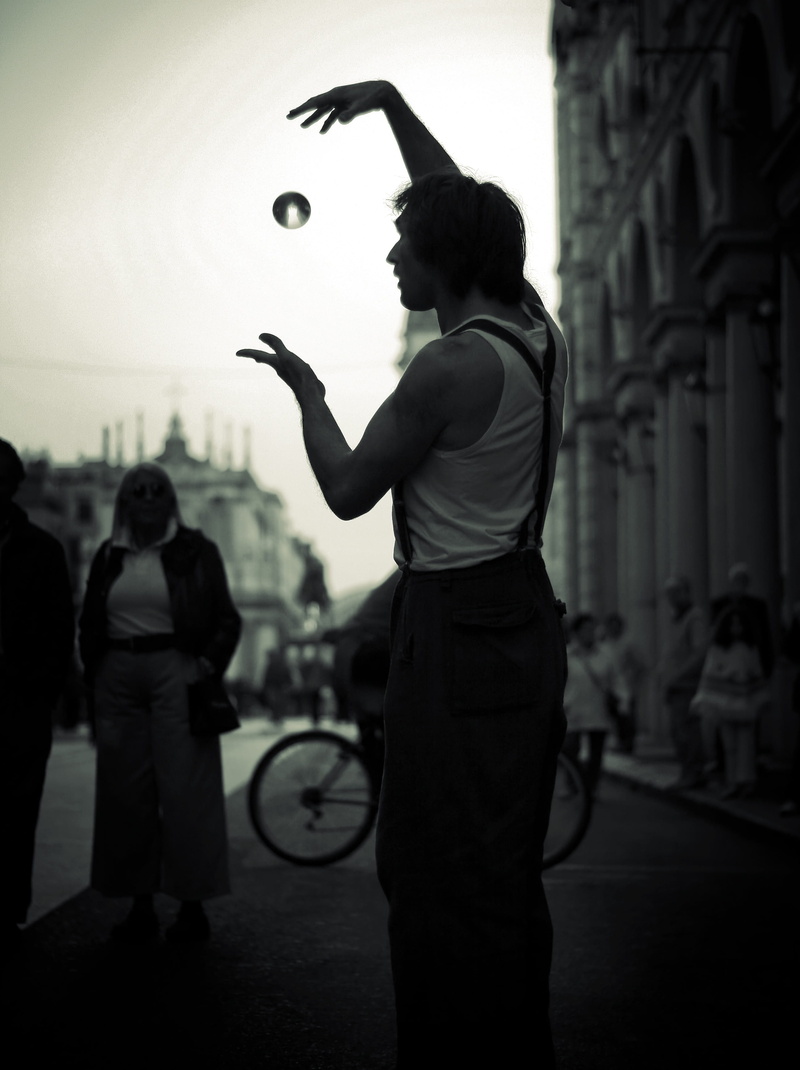standing, lifestyles, real people, day, playing, street artist, architecture, silhouette, built structure, leisure activity, clown, magic, black and white