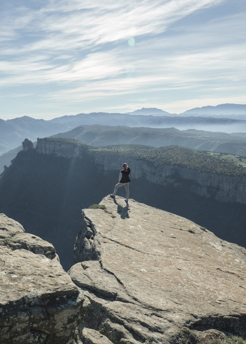 tranquil scene, cliff, standing, rock, mountain range, landscape, mountain, clouds, one person, activity, outdoors, overlooking, leisure activity, tranquility