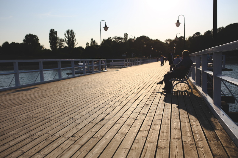 sky, leisure activity, footpath, street, seat, sea, one person, sitting, outdoors, railing, 5K, trees, summer, water, lifestyles, transportation, plant