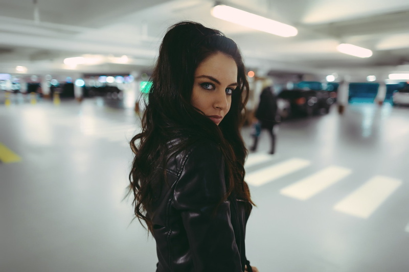 looking at viewer, blue eyes, looking over shoulder, Aurela Skandaj, 1080P, women, parking lot, brunette, leather jackets