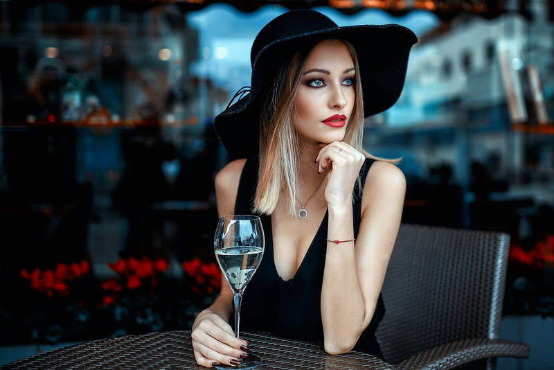 table, red lipstick, looking away, depth of field, chair, hat, Alessandro Di Cicco, blonde, 1080P, drinking glass, necklace, painted nails, blue eyes