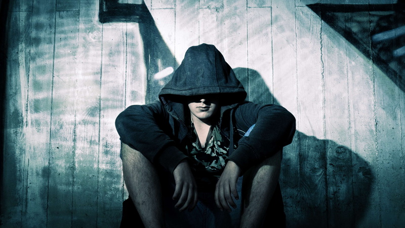 hooded shirt, shadow, real people, sitting, emotion, hood - clothing, dark, wooden, one person, three quarter length, fashion, jacket, wear, young adult