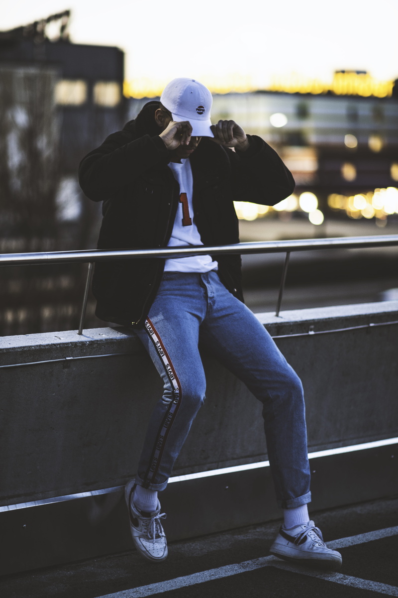 front view, outfit, jeans, architecture, casual, guy, style, blue, technology, sitting, full length, lifestyles, person, fashion, male, wear, railing, man