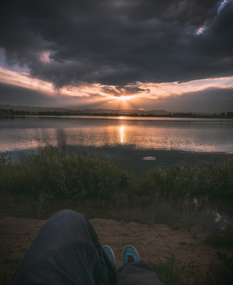 tranquil scene, sky, crepuscular, water, personal perspective, lake, real people, near, golden, beauty in nature, non-urban scene, cloud, human body part