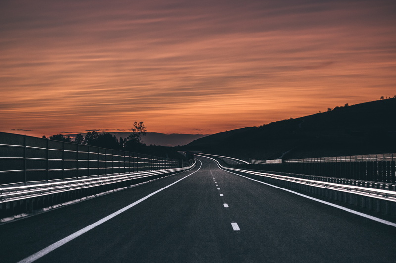 road, bridge - man made structure, marking, dividing line, highway, road marking, sky, symbol, cloud - sky, sunset, hill, no people, trees, transportation