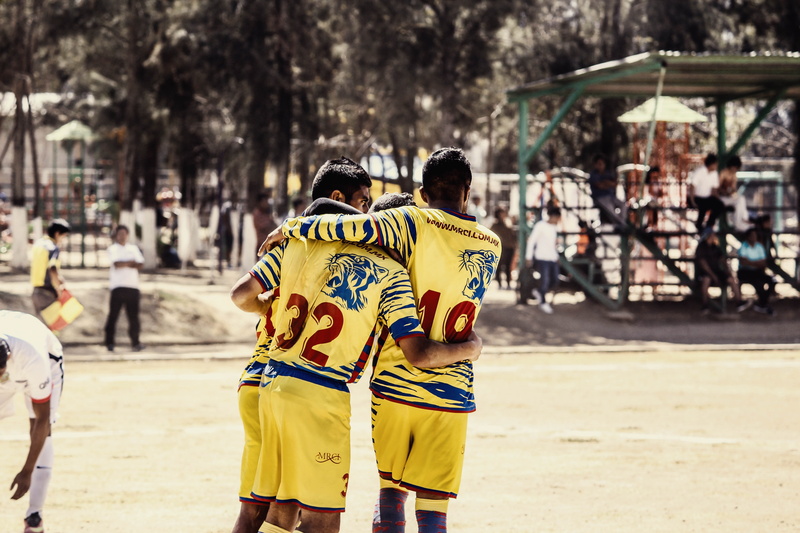 yellow, men, land, hugging, sport, holding, player, outdoors, lifestyles, incidental people, standing, nature, street, three, group of people, team, leisure activity