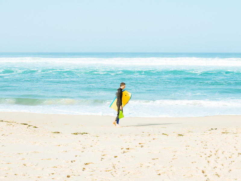 bodyboard, real people, carrying, day, holding, leisure activity, beach, yellow, horizon, seashore, holiday, motion, sky, one person, surfboard, beauty in nature