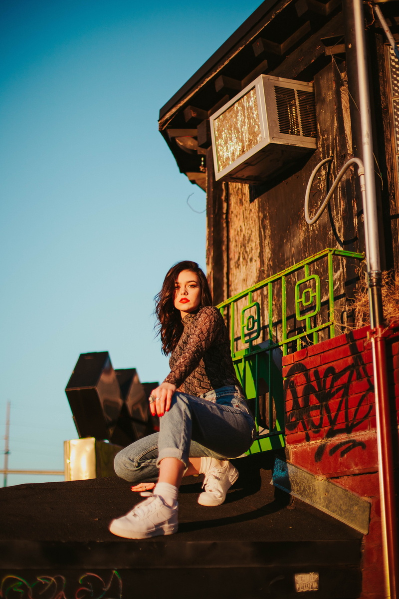 couch, outdoors, human, building exterior, blue, casual clothing, sleeve, plywood, beautiful woman, tire, young women, footwear, shirt, girl, long sleeve
