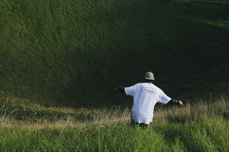 adult, land, film, looking out, ambient, looking away, lighting, boy, grass, field, volcano, dslr, hill, day, falling, 5K, unrecognizable person, crater
