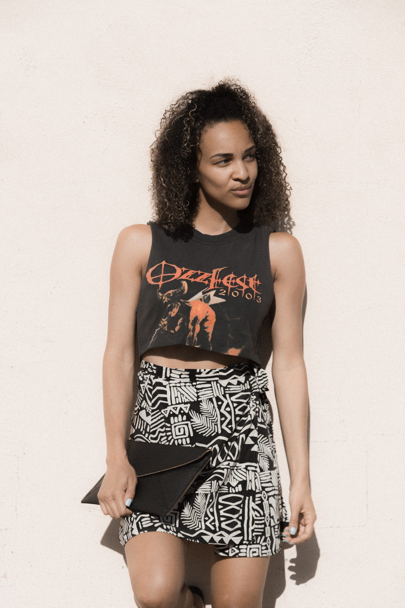 front view, young adult, text, fashion, shorts, folder, real people, style, leaning, beauty, model pose, black skin, wall - building feature, beautiful woman