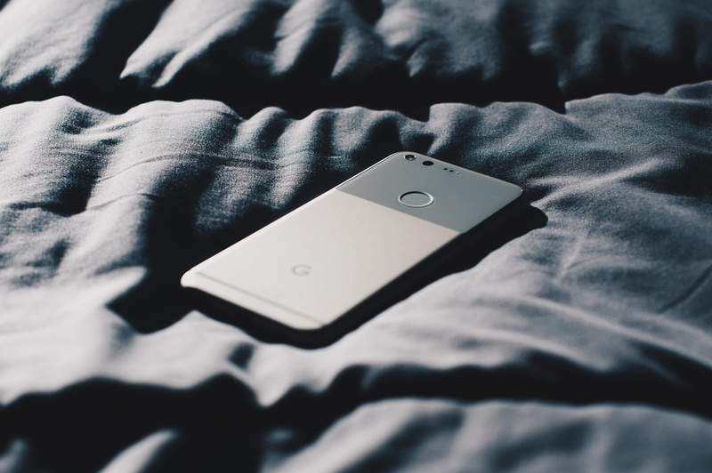 human hand, hand, smartphone, textile, grey, high angle view, arts culture and entertainment, electronic, jeans, furniture, bed, key, button, midsection