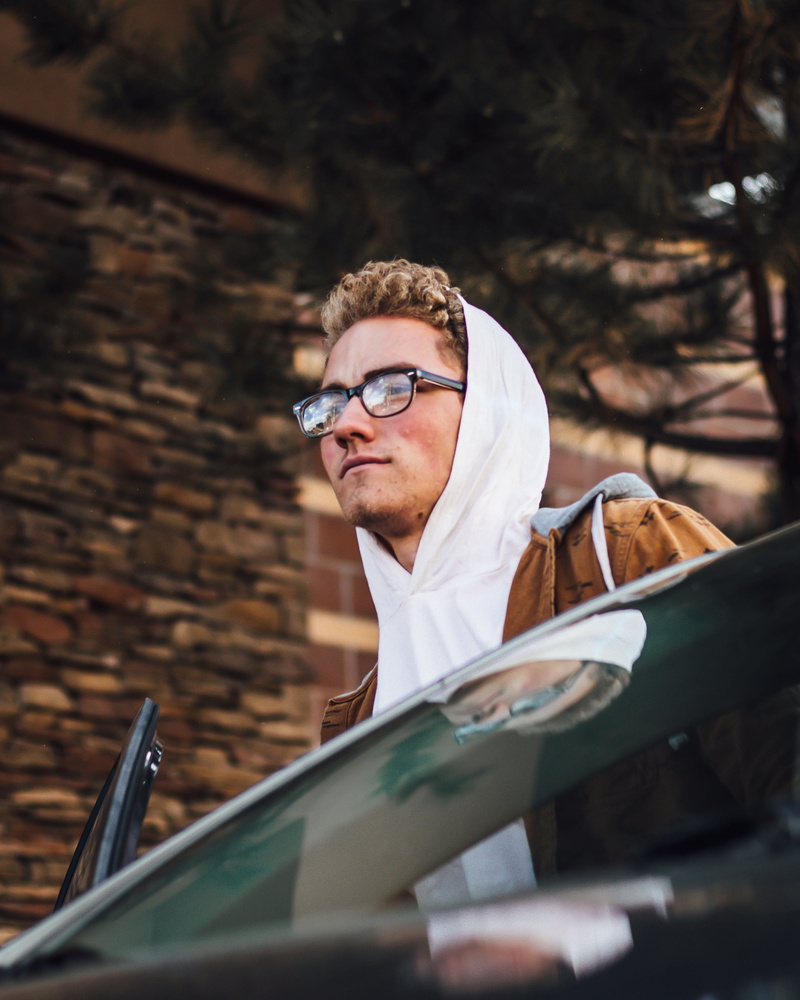 people, car, front view, man, finger, face, clothing, land vehicle, accessories, mode of transportation, guy, one person, driving, males, outdoors, men
