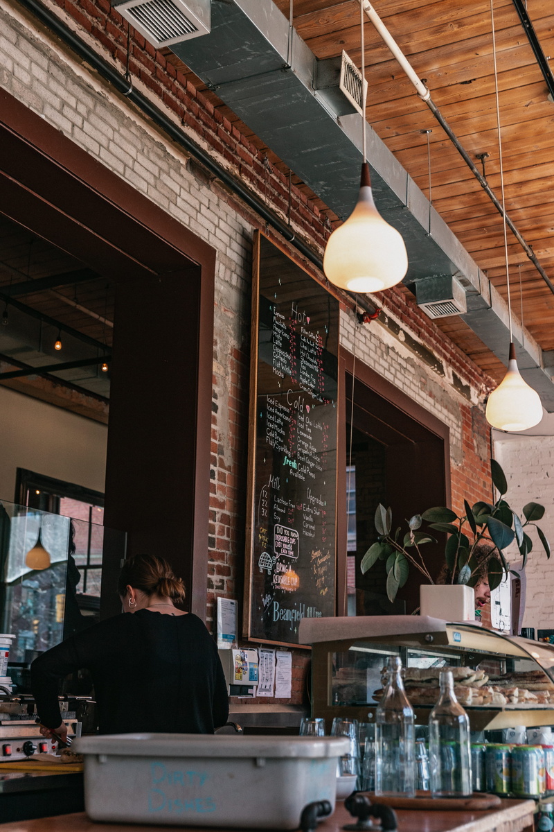 architecture, building, bar counter, person, restaurant, rear view, 5K, city, occupation, adult, lighting equipment, woman, business, electric lamp, stocks