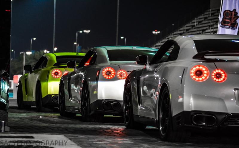 sports car, nissan nissan skyline gt r r35 nissan skyline gt r r34 nissan skyline gt r r33 car, no people, in a row, red, motor racing track, architecture