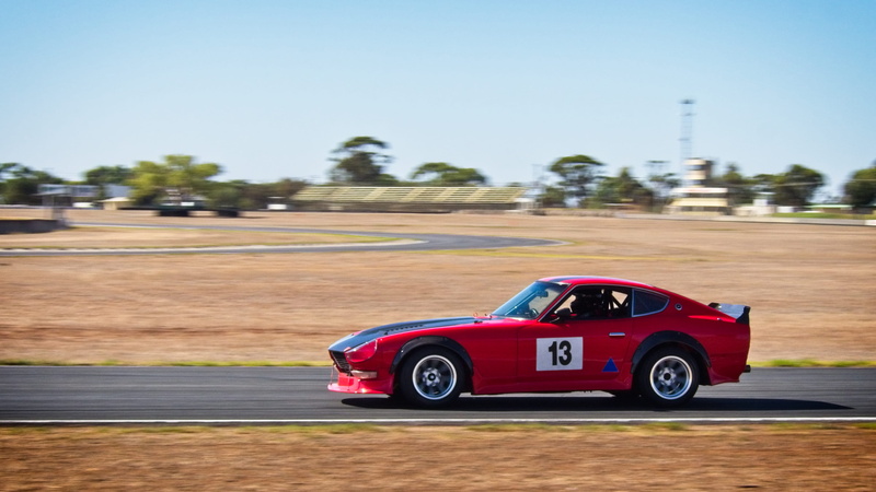sky, sports car, trees, vehicle, race track, day, automobile, red, motion, motor vehicle, motorsport, coupe, transportation system, tree, driver, sport