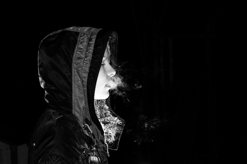 side view, clothing, smoke, darkness, contemplation, leisure activity, women, looking, young adult, black background, hood, indoors, portrait, hooded shirt