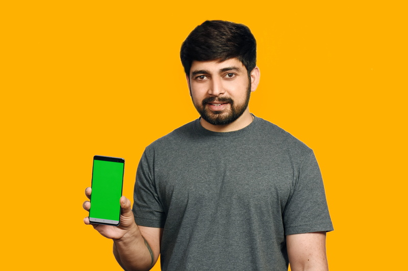 wireless technology, holding, studio shot, student, portrait, photo, yellow background, cut out, beard, human, waist up, mobile phone, casual clothing