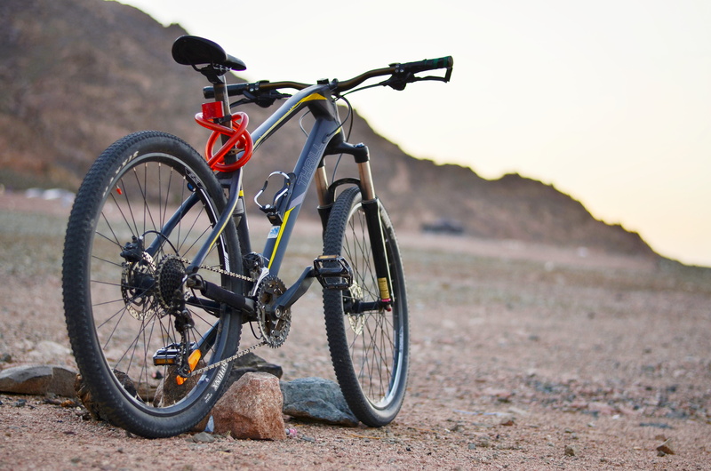 black, tire, helmet, outdoors, rock, 4K, bicycle, sunlight, mountain, stationary, sport, wheel, hardtail, sky, dirt, no people, bike, day, transportation