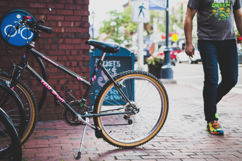 architecture, brick, building exterior, leisure activity, pedestrian, land vehicle, focus on foreground, 5K, parked, transportation, biking, beside, city life
