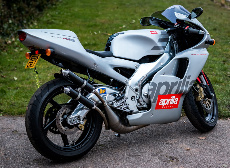 outdoors, bike, silver colored, bicycle, side view, transportation, helmet, parking, speed, street, aprilia rs250, stationary, mode of transportation, day