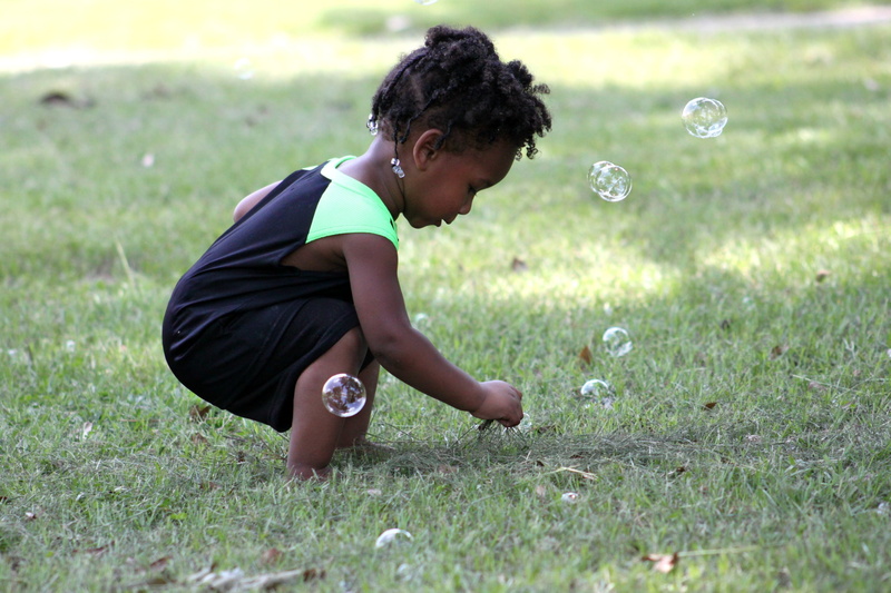 bubbles, green, green color, day, lifestyles, casual clothing, land, grass, childhood, bubble, focus on foreground, outdoors, girl, small, kid, young, rainbow bubbles
