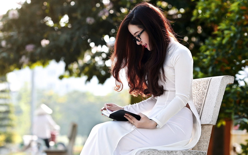sitting, hairstyle, beautiful woman, casual clothing, holding, real people, Asian, focus on foreground, reading, lifestyles, model, adult, three quarter length