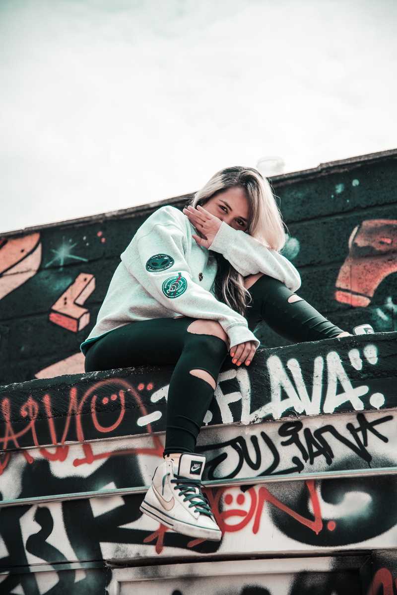 looking at camera, young women, 5K, person, hairstyle, lifestyles, one person, leisure activity, urban style, graffiti, outdoors, wear, communication