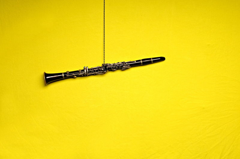 studio shot, Musical Instrument, still life, pen, metal, black color, wall - building feature, close-up, Clarinet, Yellow Background, directly above, colored background