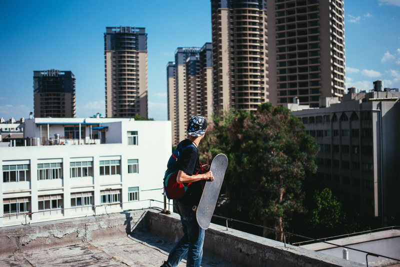 view from side, urban, built structure, extreme, building, residential district, recreation, 2K, sunlight, athletic, skater, young, rooftop, sitting, sports