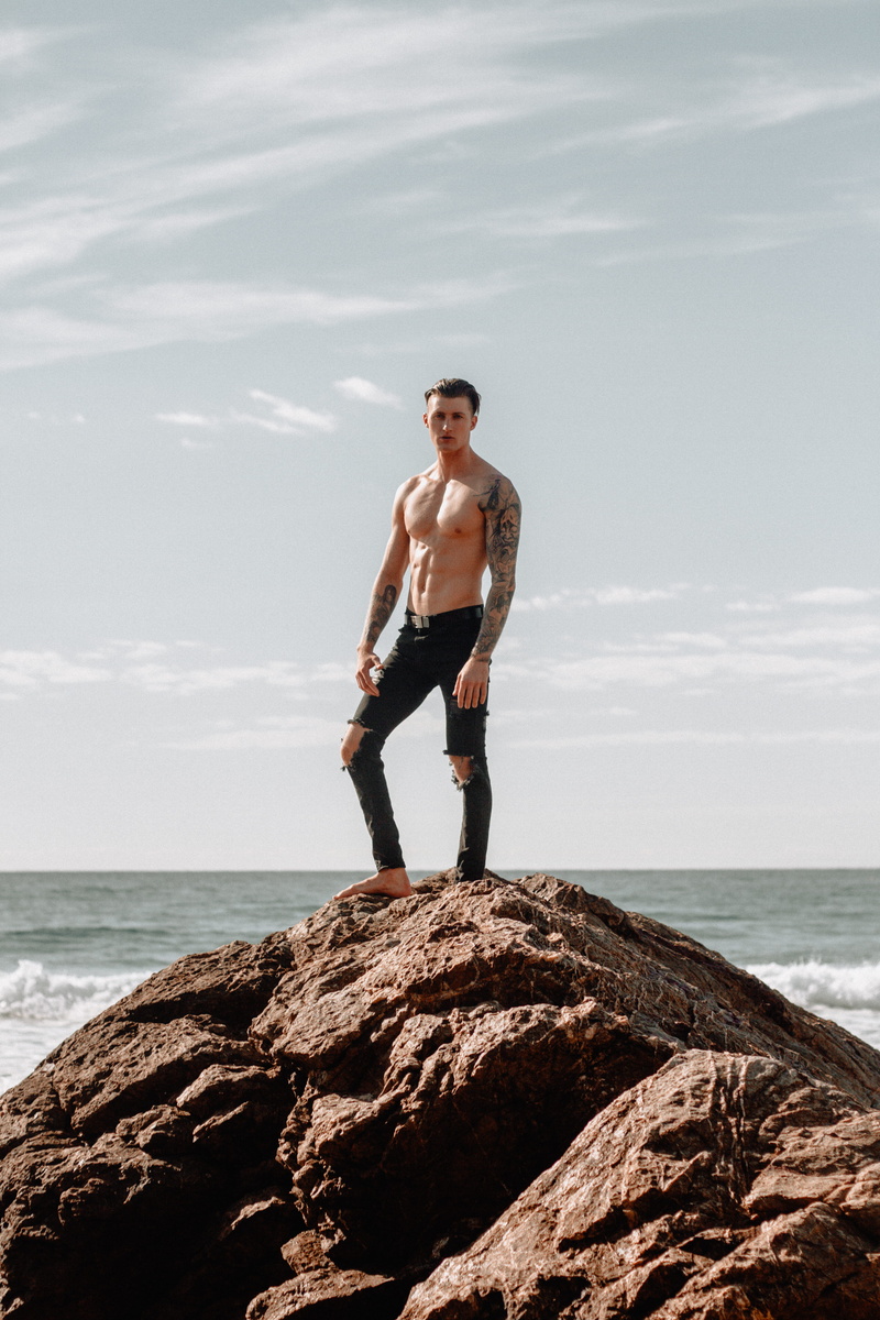 leisure activity, land, tattoo, good, male, water, model, daytime, flex, solid, sea, outdoors, jeans, horizon over water, nature, young men, hill, one person