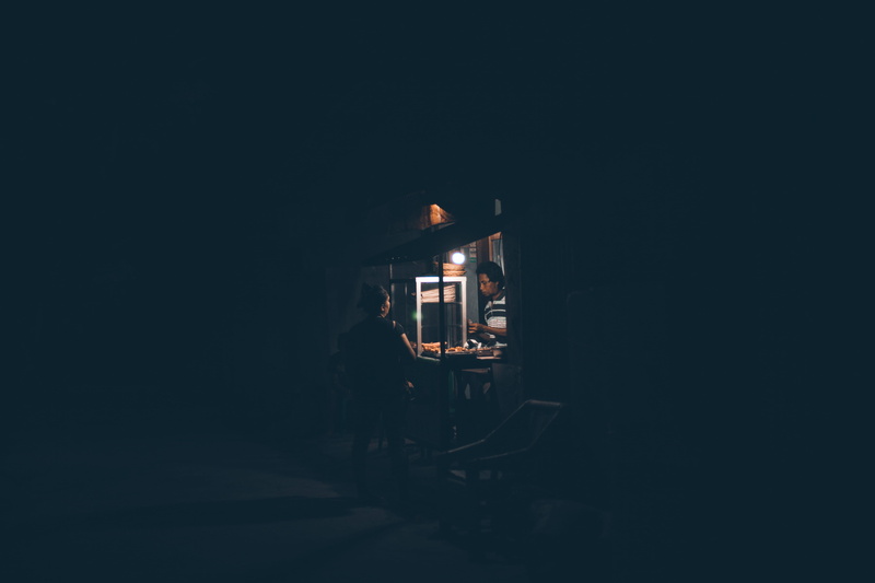close, sausage, moments, real people, building, blue, sell, night, one person, person, lifestyles, copy space, selling, dark, store, men, bread, sale, illuminated