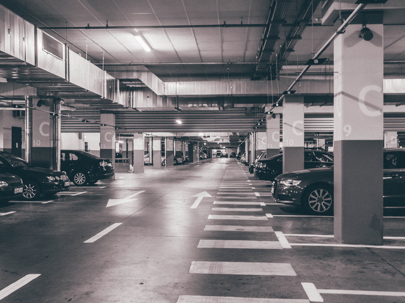 parking garage, direction, mode of transportation, vehicles, parking area, black, built structure, motor vehicle, architectural column, sign, land vehicle