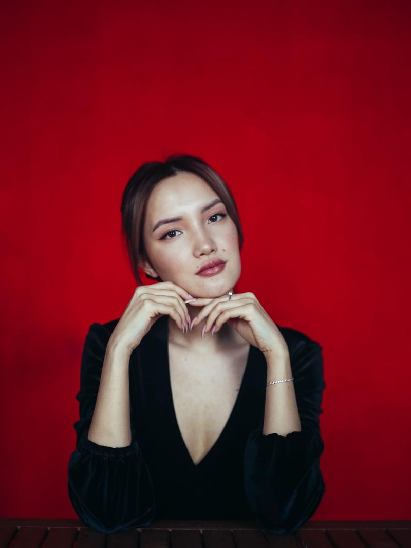 one person, astana, young adult, evening dress, sitting, near, gown, portrait, colored background, looking at camera, casual clothing, red, photography