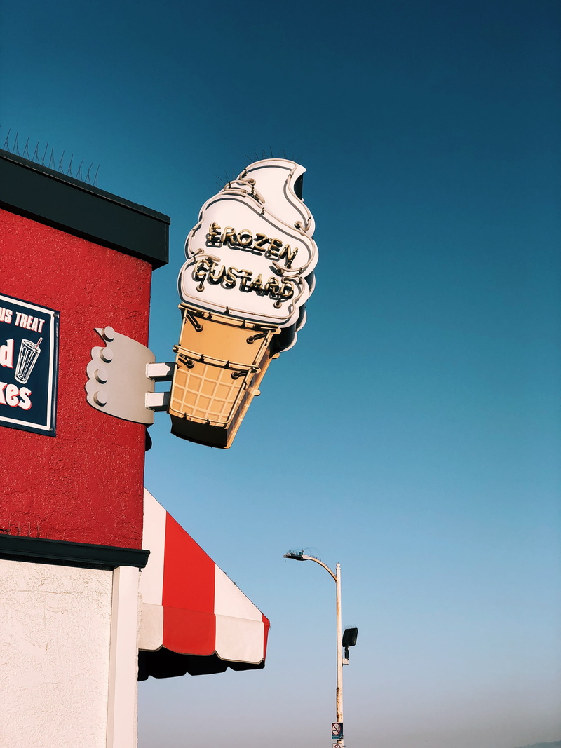 sky, low angle view, sign, building exterior, frozen, street, architecture, poster, nature, la, clear sky, communication, sunlight, motel, trademark, blue